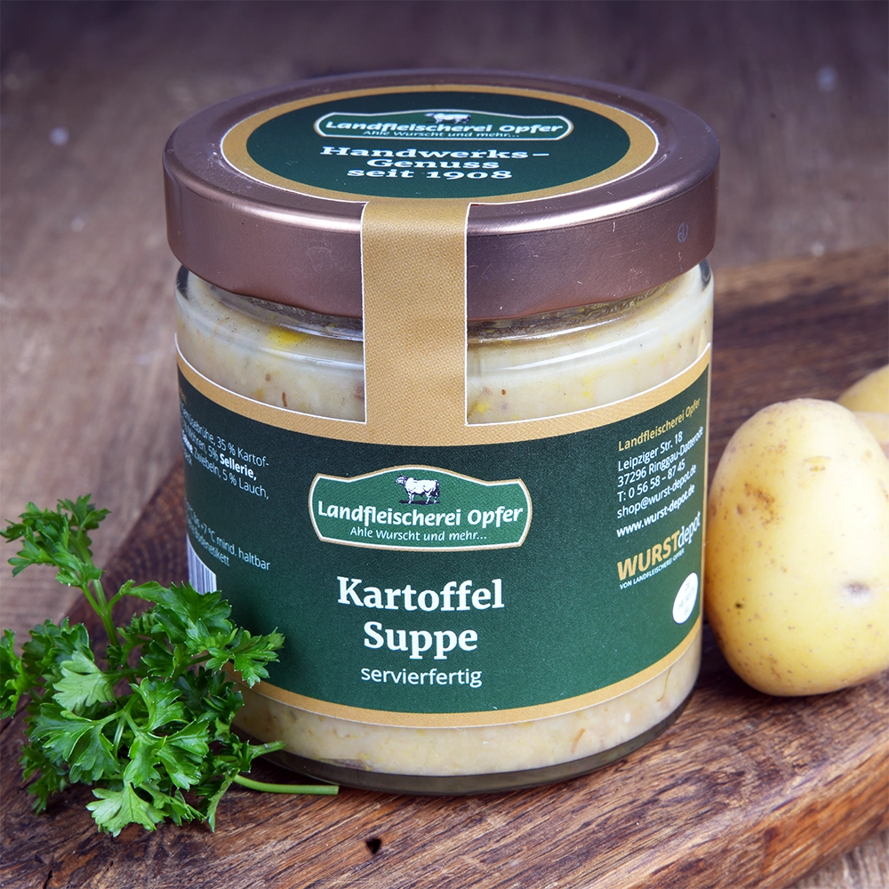 Ein Glas Kartoffelsuppe mit Schraubverschluss und grünem Etikett steht auf einem Holzbrett. Daneben liegen Petersilie und Kartoffeln.