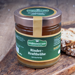 Ein Glas Rinder-Kraftbrühe mit Schraubverschluss steht auf einem Holzbrett. Daneben liegen Brotscheiben.