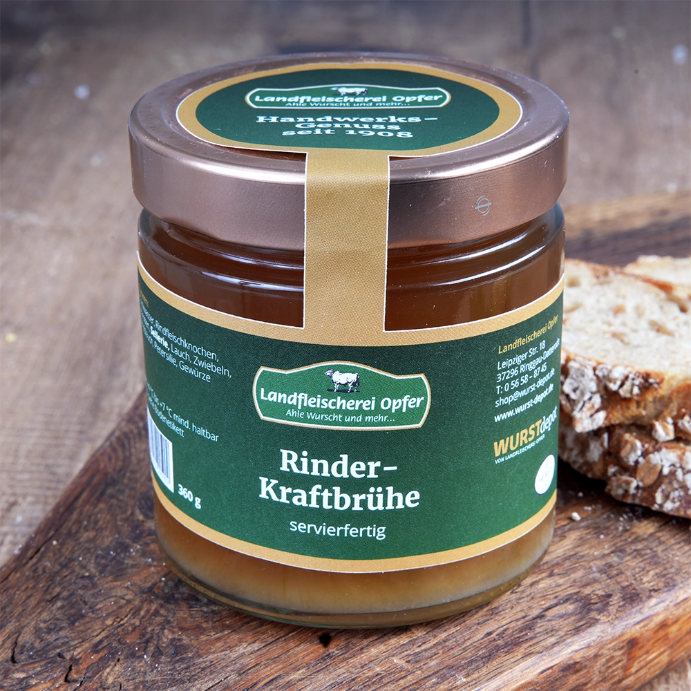 Ein Glas Rinder-Kraftbrühe mit Schraubverschluss steht auf einem Holzbrett. Daneben liegen Brotscheiben.